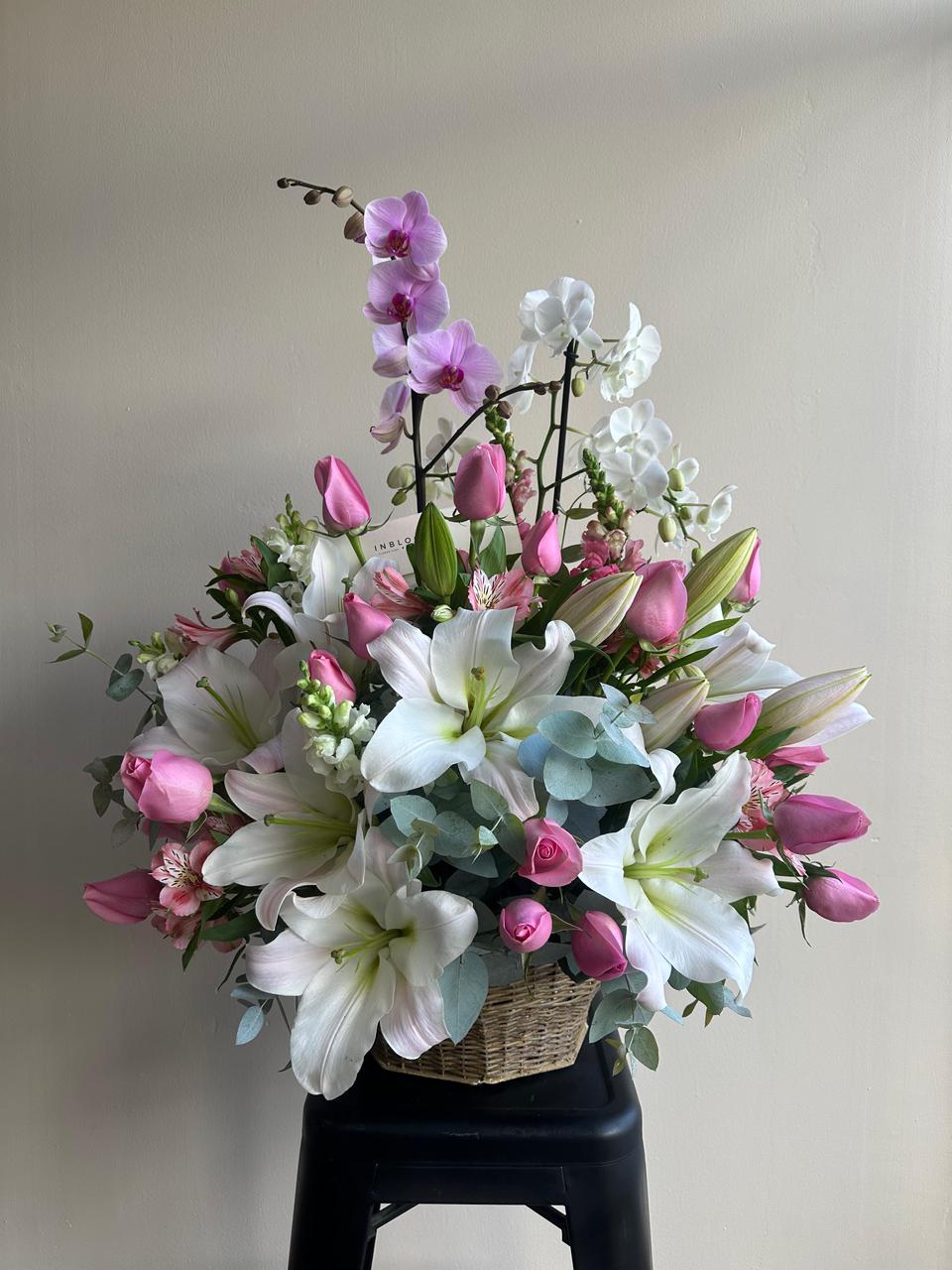 Canasta floral premium con lirios, rosas y orquídeas en canasta de mimbre — InBloom Guatemala